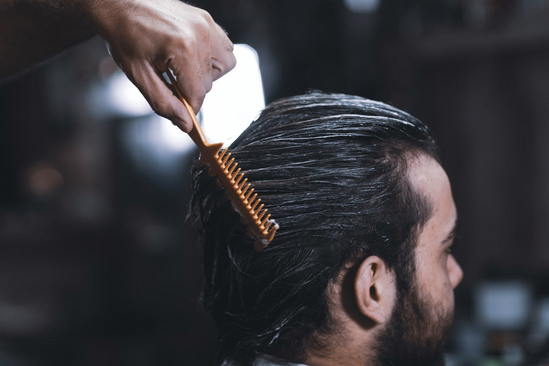 Professional hairstylist applying a non-surgical hair replacement system to a male client at Kaelyss in Chicago, ensuring a natural and seamless look.